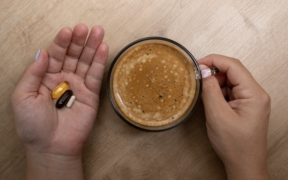 kubek kawy i lekarstwo na dłoni